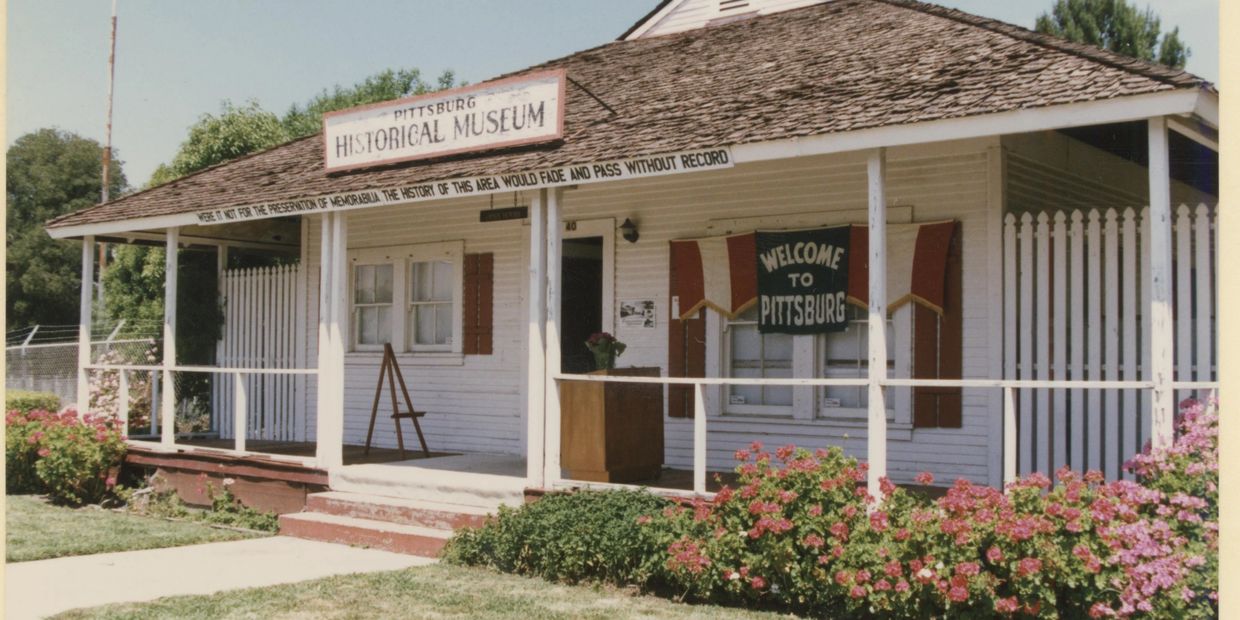 Exterior view of the Pittsburg Historical Museum with welcoming signs and flowers
